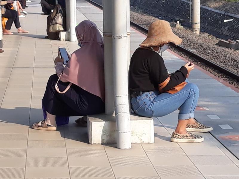 Tunggu KRL & Hindari Panas, Penumpang Duduk di Samping Tiang Stasiun Bekasi Timur