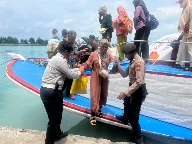 Anggota Polsek Kepulauan Seribu Utara Bantu Penumpang Turun Kapal di Dermaga Pulau Kelapa